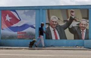 Un hombre camina frente a un fotografía del presidente de la República de Cuba, Miguel Díaz-Canel, junto al exmandatario cubano Raúl Castro, en La Habana (Cuba). EFE/Ernesto Mastrascusa