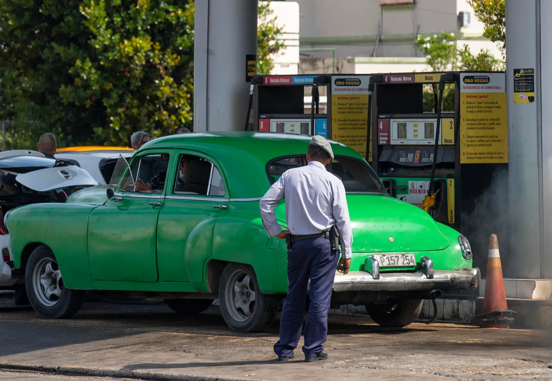 Un policía (de espaldas) observa a un coche antiguo en una gasolinera, hoy en La Habana (Cuba). EFE/Yander Zamora
