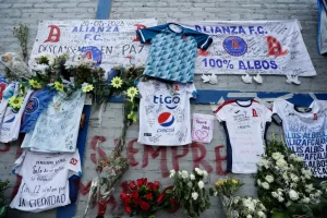 Fotografía de camisetas y flores en un homenaje a los aficionados fallecidos tras una estampida humana durante un partido entre Alianza y el Futbolistas Asociados Santanecos el pasado sábado, en las afueras del Estadio Cuscatlán, en San Salvador (El Salvador). EFE/Rodrigo Sura