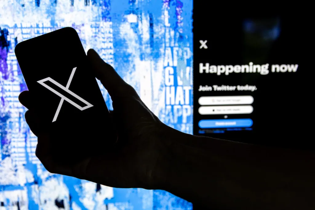 Fotografía de archivo donde se muestra a un usuario mientras sostiene un teléfono móvil que muestra el logotipo de la página 'X', llamada antes Twitter. EFE/ Etienne Laurent