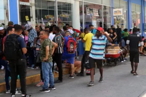Migrantes hacen fila afuera de una casa de cambio, en la ciudad de frontera de Tapachula, Chiapas (México). EFE/ Juan Manuel Blanco