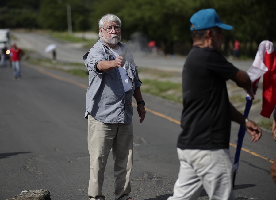 Un hombre dispara un arma hacia un manifestante en medio de un bloqueo de docentes en la vía Panamericana hoy, en Chame (Panamá). EFE/ Bienvenido Velasco