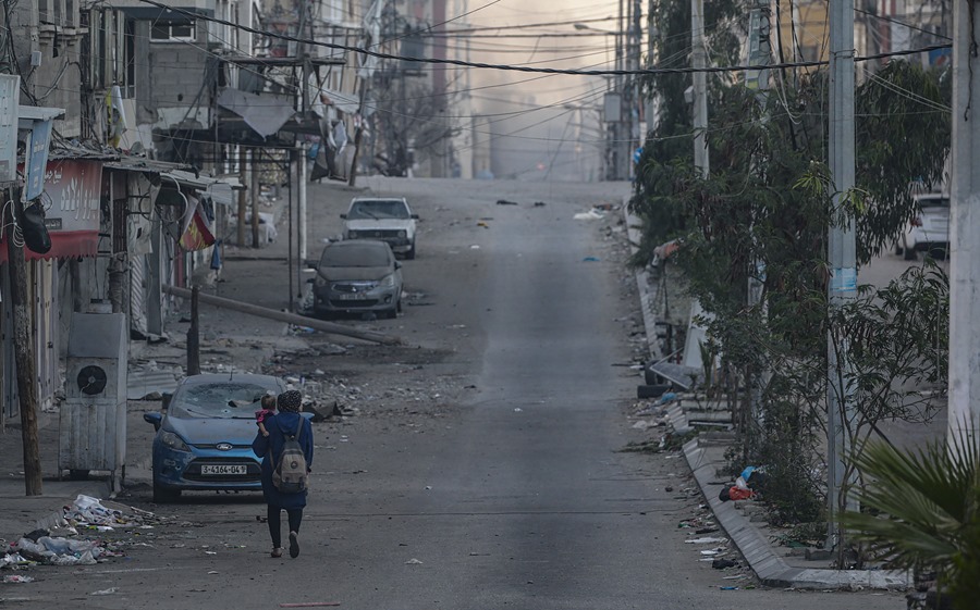 Una mujer camina con un niño por una calle de Gaza,tras los ataques aéreos israelíes. EFE/EPA/Mohammed Saber