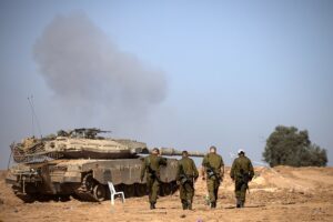 Un grupo de soldados israelíes camina cerca de un tanque en la frontera con la Franja de Gaza. EFE/EPA/Christophe Petit Tesson