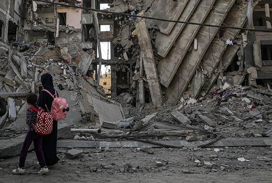 Una mujer y una niña caminan entre edificios destrozados por bombardeos israelíes en Gaza. EFE/EPA/Mohammed Saber