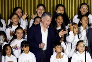 El expresidente de Colombia Juan Manuel Santos canta junto al "Coro de hijas e hijos por la paz", conformado por niños de los firmantes del acuerdo de paz, durante la conmemoración de los siete años de la firma de ese acuerdo entre Colombia y la guerrilla de las FARC, hoy, en el Centro Nacional de Memoria Histórica (CNMH) en Bogotá (Colombia). EFE/ Mauricio Dueñas Castañeda
