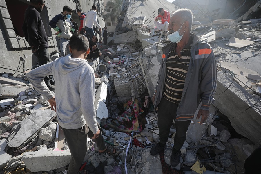 El cuerpo de un hombre (c) yace cubierto por una manta entre los escombros de la casa destruida de las familias Al Madfaa y Shabit tras los ataques aéreos israelíes al campo de refugiados de Al Maghazi , sur de la Franja de Gaza, este lunes. EFE/Mohammed Saber