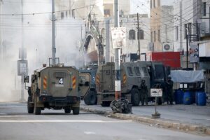 Soldados israelíes se protegen de los artefactos explosivos lanzados por los palestinos durante una incursión del ejército israelí en el campo de refugiados de Askar. EFE/EPA/Alaa Badarneh