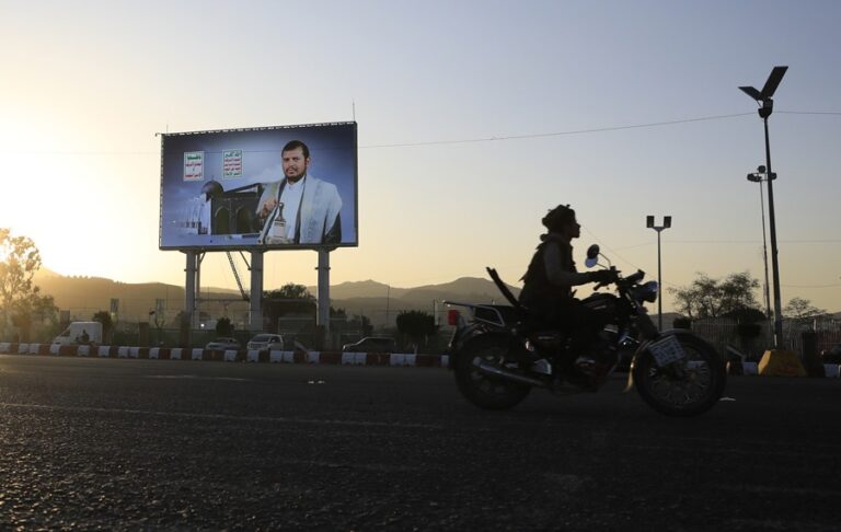 Un motociclista pasa junto a un cartel con la imagen del máximo líder de los hutíes, Abdul-Malik al-Houthi, en Saná. EFE/EPA/Yahya Arhab
