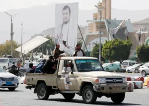 Simpatizantes hutíes viajan en un vehículo pasando junto a una pancarta que representa al máximo líder hutí, Abdul-Malik al-Houthi, en una fotografía de archivo. EFE/EPA/Yahya Arhab