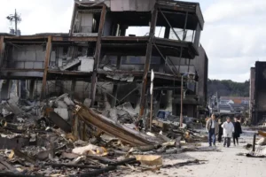 Personas caminan junto a restos quemados de estructuras de edificios tras un terremoto en Wajima, prefectura de Ishikawa (Japón). EFE/EPA/Franck Robichon