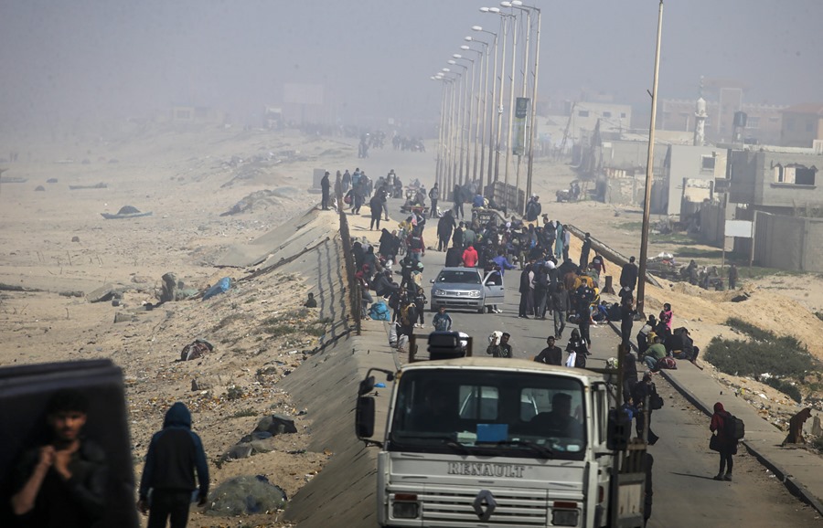El polvo y el humo de los ataques aéreos envuelven a los palestinos que caminan por la carretera Al Rashid huyendo de los combates en el norte de la Franja de Gaza. EFE/EPA/Mohammed Saber