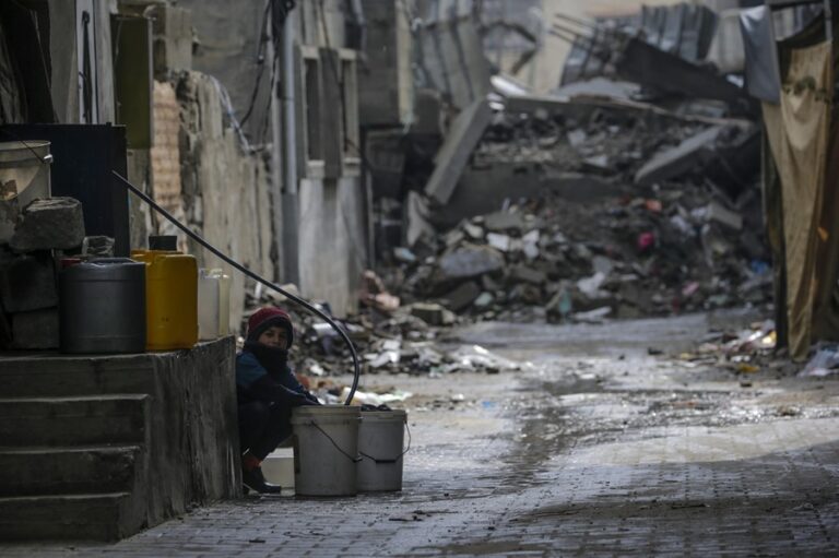 Un niño llena un cubo con agua entre escombros en el campo de refugiados de Al Nusairat, en el sur de la Franja de Gaza. EFE/EPA/Mohammed Saber