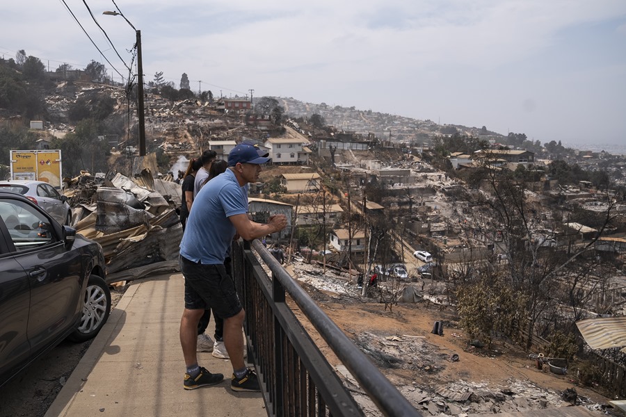 Un grupo de personas fue registrado al observar los estragos y las viviendas destruidas por los incendios forestales, en el sector de Achupallas, en Viña del Mar (Valparaiso (Chile). EFE/Adriana Thomasa