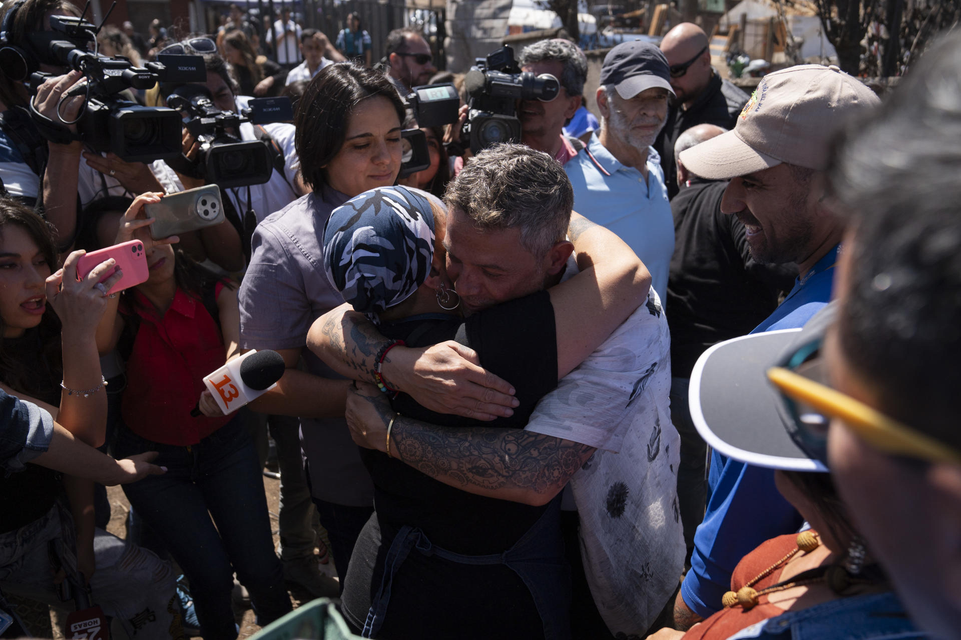 El cantante español Alejandro Sanz abraza a una mujer en Villa Independencia, uno de los sectores afectados por los recientes incendios en la región, en Viña del Mar (Chile). EFE/Adriana Thomasa