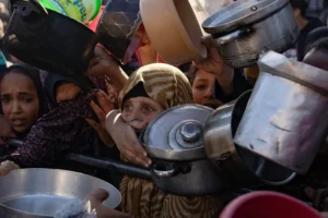 Palestinos desplazados recogen alimentos donados por un grupo juvenil benéfico, en el sur de la Franja de Gaza. EFE/EPA/Haitham Imad