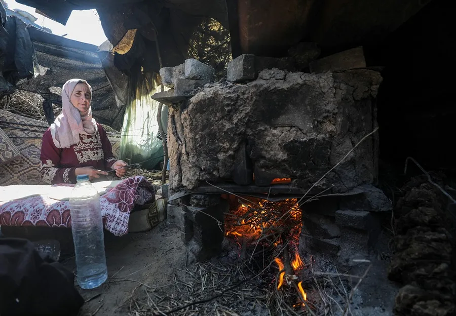 Una mujer palestina desplazada internamente hornea pan en un horno en Deir Al Balah, al sur de la Franja. EFE/EPA/Mohammed Saber