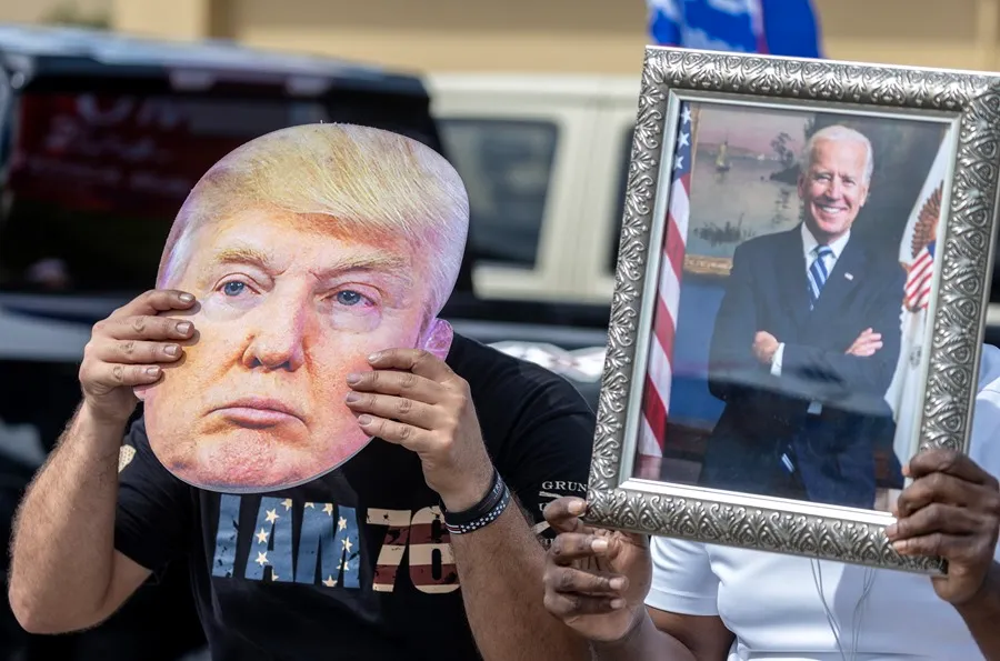 Un partidario de Joe Biden sostiene un retrato del presidente estadounidense (der) junto a un seguidor de Donald Trump que lleva una foto del exmandatario (izq) en Florida (EE.UU.) EFE/Cristóbal Herrera-Ulashkevich