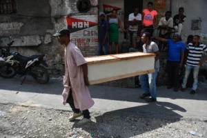 Dos personas cargan un cajón para recoger el cuerpo de una persona en la calle, el 20 de marzo de 2024, en Puerto Príncipe (Haití). EFE/ Johnson Sabin