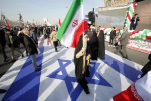 Una mujer iraní sostiene la bandera nacional de Irán mientras camina sobre la bandera de Israel, en una fotografía de archivo. EFE/ Abedin Taherkenareh