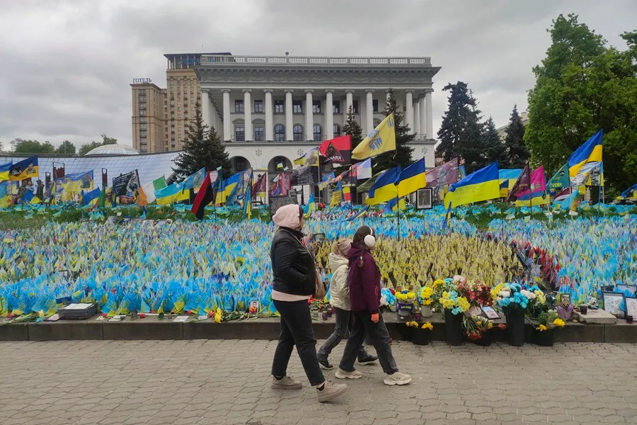 Una mujer y dos niñas pasan por delante de unas banderas que recuerdan a los soldados ucranianos caídos desde el comienzo de la invasión rusa de Ucrania en el centro de Kiev. EFE/ Marcel Gascón