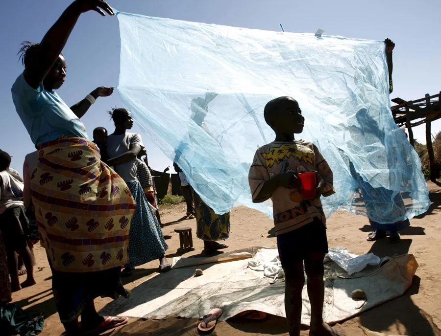 Una familia estirando una red antimosquitos en Matongo (Zambia), en una imagen de archivo. EFE/Kim Ludbrook