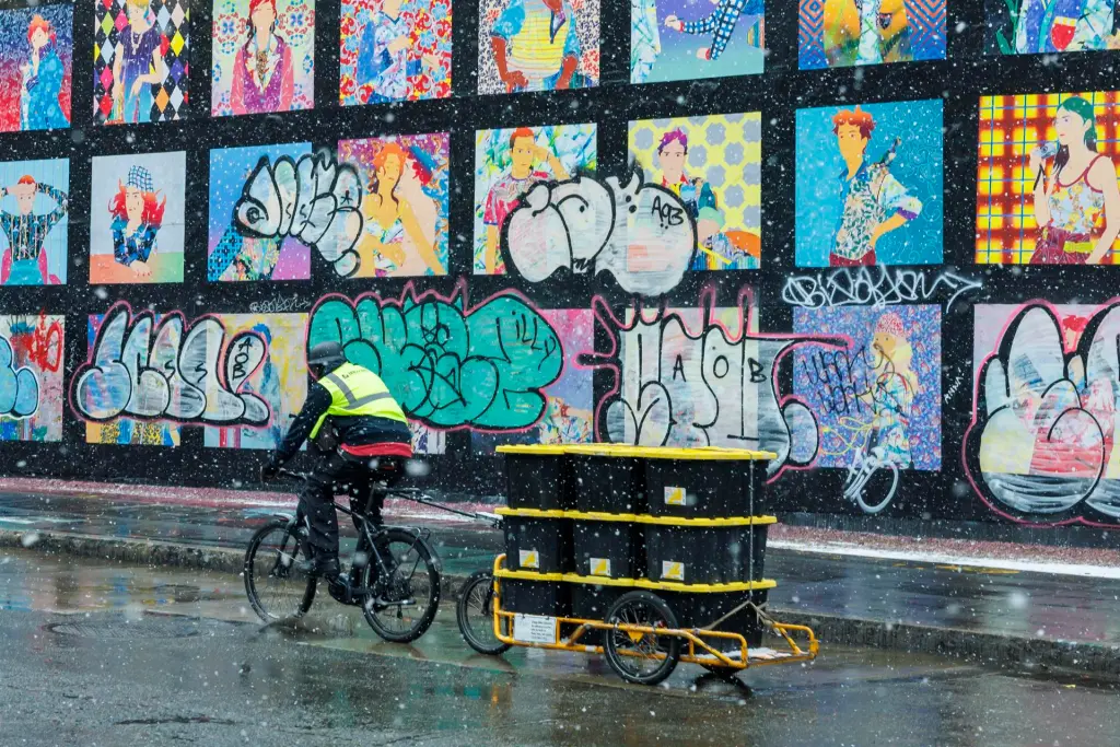 Un repartidor pasa por un mural mientras cae nieve en Nueva York, en una fotografía de archivo. EFE/EPA/Sarah Yenesel