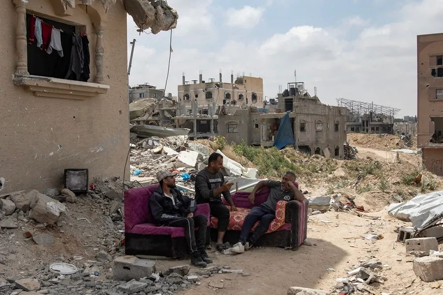 Palestinos se sientan en un sofá junto a las ruinas de su casa destruida en Jan Yunis. EFE/EPA/Haitham Imad