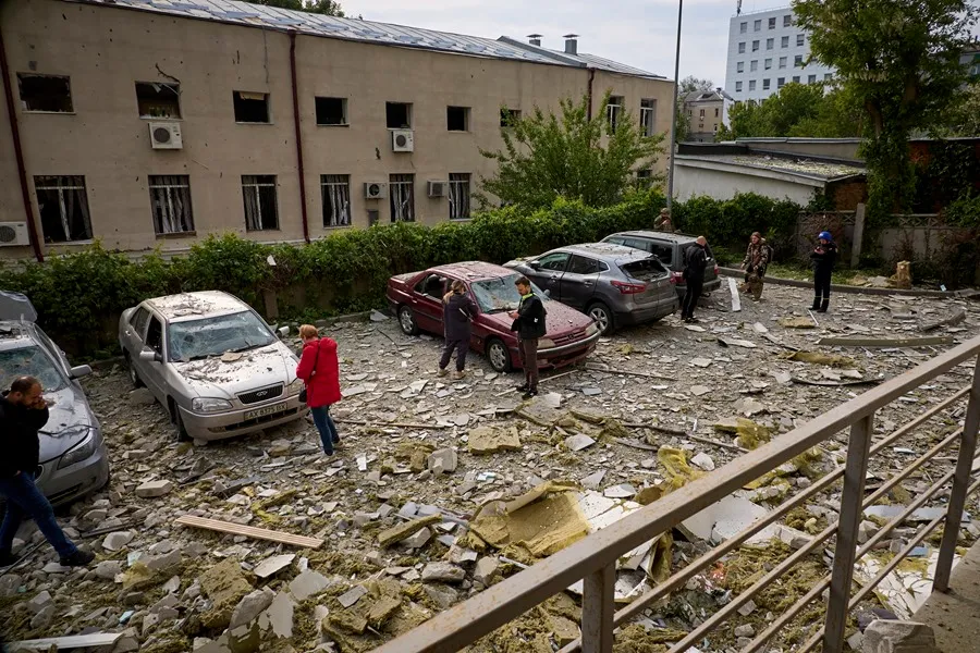 La gente inspecciona sus automóviles estacionados cerca del lugar de un bombardeo en una zona residencial de Jarkov. EFE/EPA/Sergey Kozlov