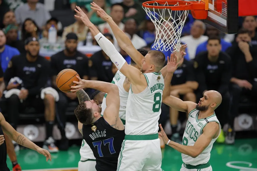 El jugador de los Boston Celtics Kristaps Porzingis (C) bloquea un tiro de los Dallas Mavericks Luka Doncic (i). EFE/EPA/CJ GUNTHER SHUTTERSTOCK FUERA