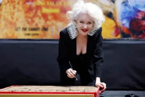 La cantante y compositora Cyndi Lauper firma una losa de cemento durante la ceremonia de huellas en Los Ángeles. EFE/EPA/CAROLINE BREHMAN