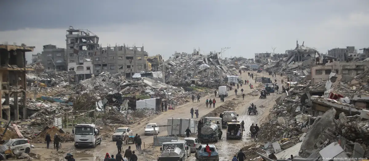 Coches y peatones circulan por un avenida en la ciudad de Gaza en medio de la devastación generalizada causada por la ofensiva terrestre y aérea del ejército israelí contra Hamás.